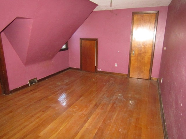 additional living space featuring wood-type flooring and vaulted ceiling