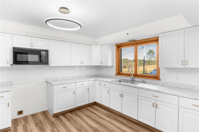 kitchen with sink, light hardwood / wood-style floors, decorative backsplash, and white cabinetry