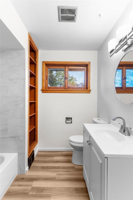 bathroom with a bathtub, toilet, vanity, and wood-type flooring