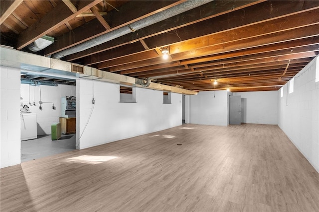 basement featuring washer / clothes dryer, electric panel, and hardwood / wood-style floors