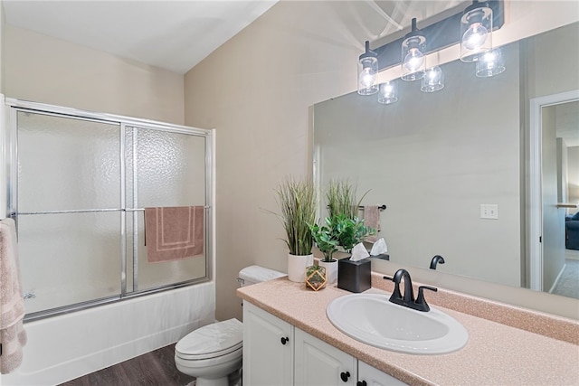 full bathroom featuring hardwood / wood-style floors, toilet, vanity, and enclosed tub / shower combo