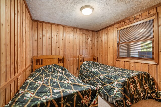 bedroom with carpet floors, wooden walls, and a textured ceiling