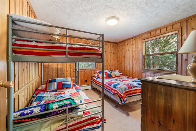 bedroom with wooden walls, baseboard heating, carpet flooring, and a textured ceiling