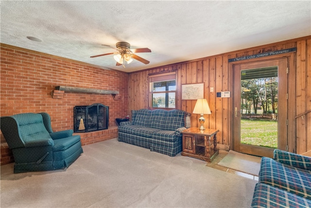 living room featuring a brick fireplace, wooden walls, light carpet, and a textured ceiling