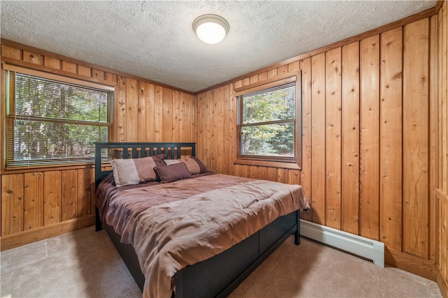 bedroom with carpet floors, a baseboard heating unit, wooden walls, and a textured ceiling