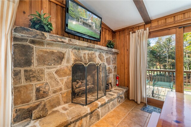 interior details featuring tile patterned floors, beam ceiling, wood walls, and a stone fireplace