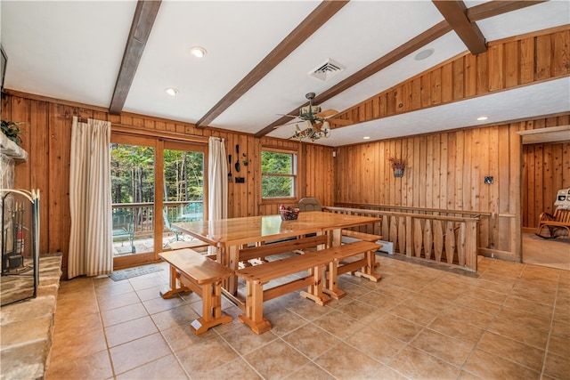 dining space featuring ceiling fan, light tile patterned flooring, wood walls, and lofted ceiling with beams