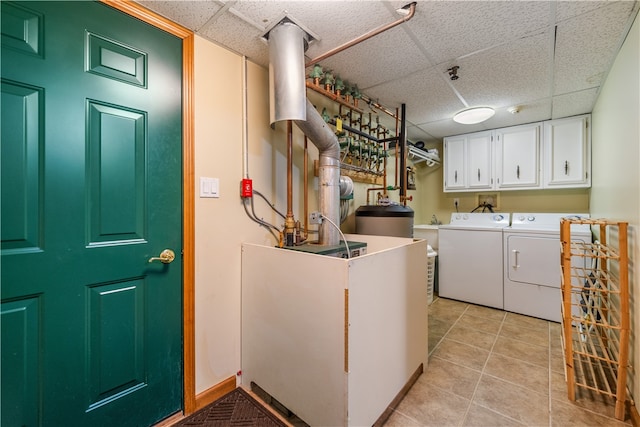 washroom featuring washing machine and dryer, light tile patterned flooring, and cabinets