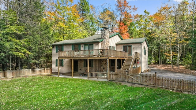 rear view of property featuring a deck, a lawn, and a patio area