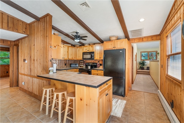 kitchen featuring black appliances, wood walls, a kitchen bar, beam ceiling, and a baseboard radiator