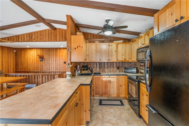 kitchen with black appliances, wooden walls, sink, tile counters, and vaulted ceiling with beams