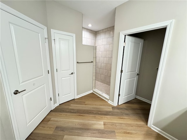 bathroom with wood-type flooring and tiled shower