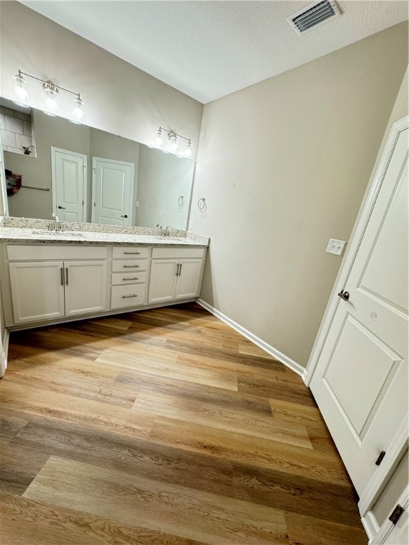 bathroom with hardwood / wood-style floors, vanity, and a textured ceiling