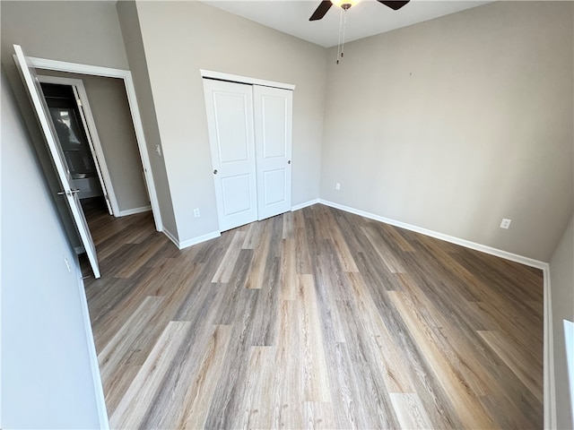 unfurnished bedroom featuring hardwood / wood-style flooring, ceiling fan, and a closet