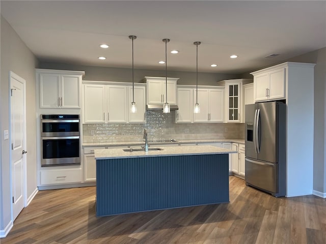 kitchen with pendant lighting, a center island with sink, white cabinetry, stainless steel appliances, and dark hardwood / wood-style flooring