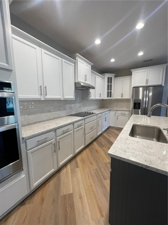 kitchen with light stone countertops, stainless steel appliances, sink, light hardwood / wood-style floors, and white cabinetry