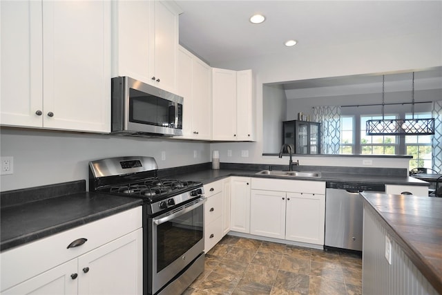 kitchen with white cabinets, appliances with stainless steel finishes, sink, and decorative light fixtures