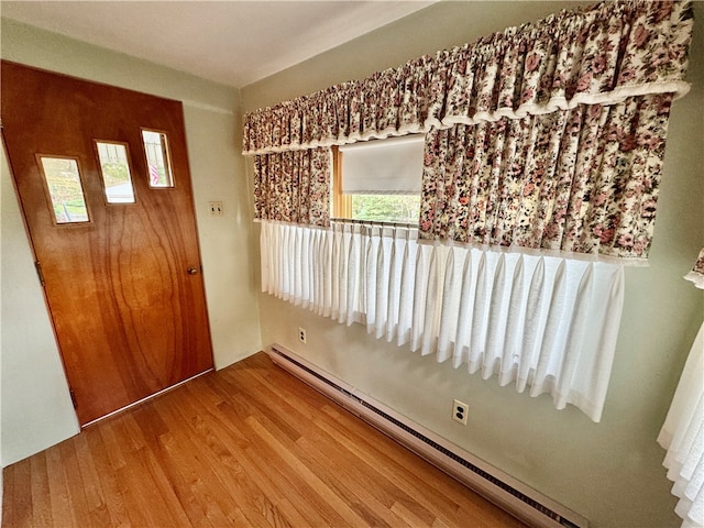 unfurnished room with hardwood / wood-style flooring and baseboard heating