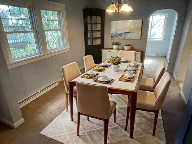 dining room featuring a healthy amount of sunlight, carpet floors, a baseboard heating unit, and an inviting chandelier