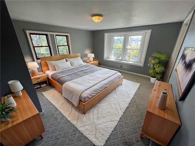 bedroom with dark colored carpet and multiple windows