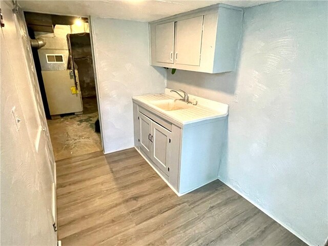 laundry area with light hardwood / wood-style flooring and sink