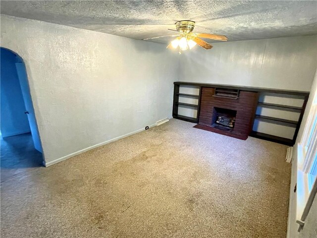 unfurnished living room featuring ceiling fan, light colored carpet, a textured ceiling, and a fireplace