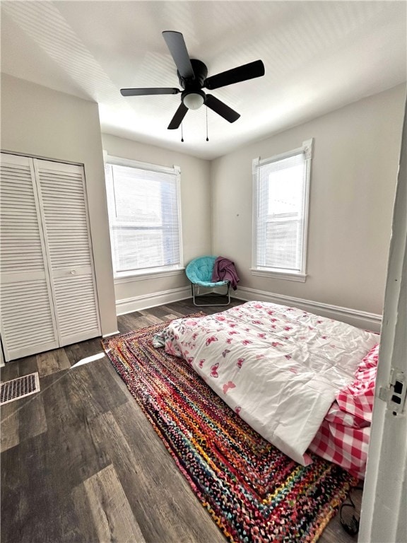 bedroom featuring a closet, ceiling fan, multiple windows, and dark hardwood / wood-style flooring