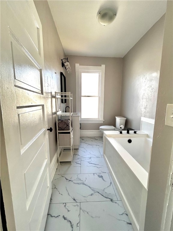 bathroom with a tub to relax in, vanity, and toilet