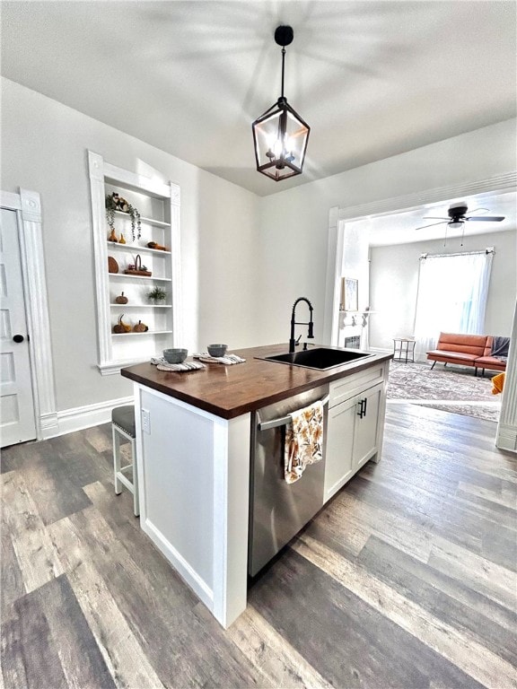 kitchen with hanging light fixtures, white cabinetry, a kitchen island with sink, stainless steel dishwasher, and sink