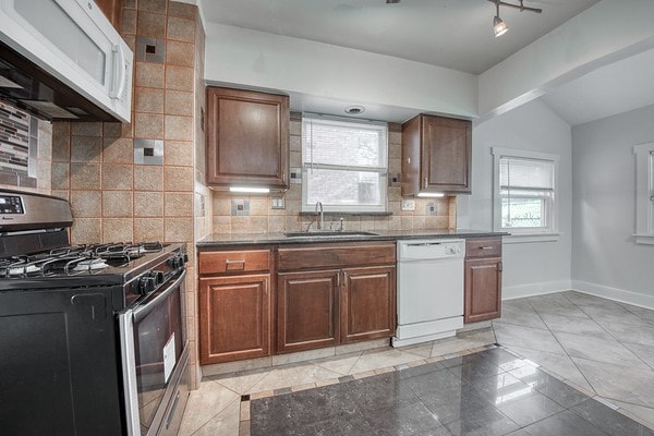 kitchen with tasteful backsplash, white appliances, lofted ceiling, and sink