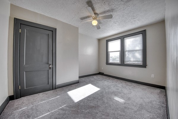 carpeted empty room featuring ceiling fan and a textured ceiling