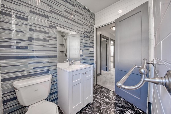 bathroom featuring tile walls, vanity, and toilet