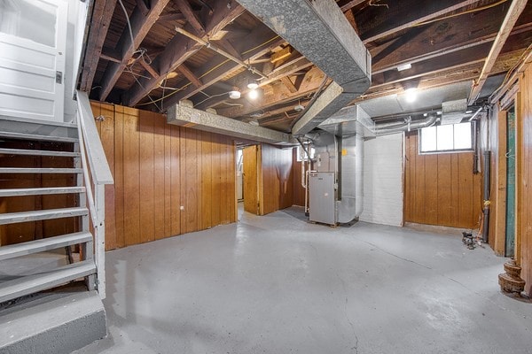 basement featuring wood walls and heating unit