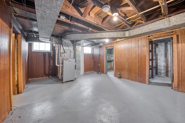 basement featuring heating unit and wood walls