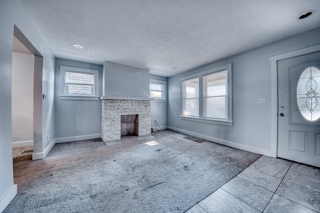 unfurnished living room with a fireplace, light colored carpet, and a textured ceiling