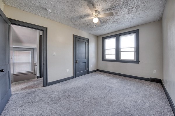 unfurnished bedroom with light carpet, ceiling fan, and a textured ceiling