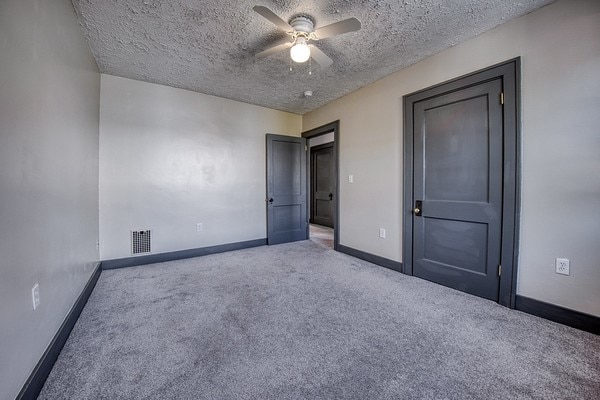 unfurnished bedroom featuring ceiling fan, a textured ceiling, and carpet flooring