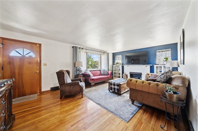 living room with a brick fireplace and light hardwood / wood-style floors