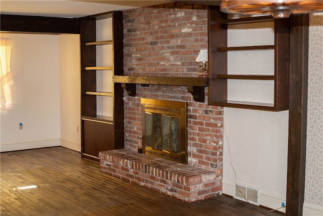 unfurnished living room featuring a brick fireplace, built in features, and dark wood-type flooring