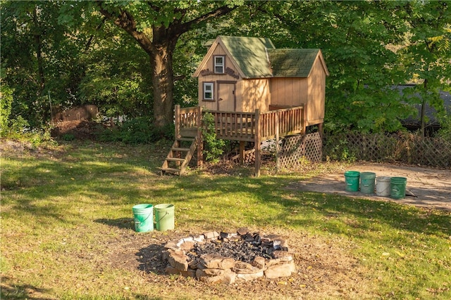 view of yard with an outdoor fire pit, a deck, and an outdoor structure