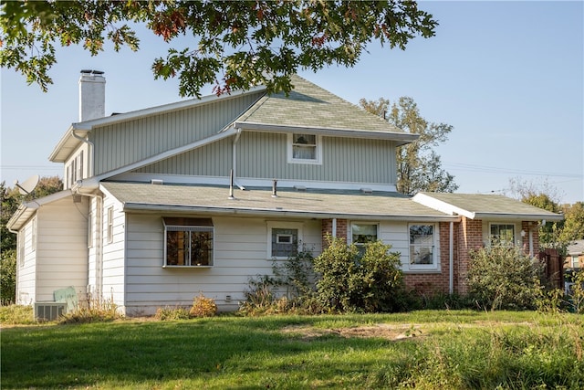 rear view of property featuring a yard and cooling unit