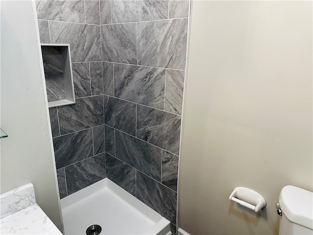 bathroom featuring toilet and a tile shower