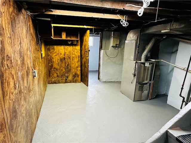 basement featuring wood walls and heating unit