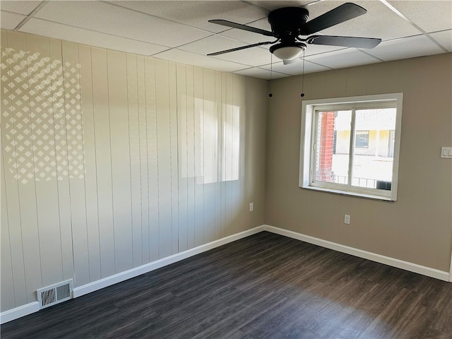 spare room with dark hardwood / wood-style flooring, a drop ceiling, and ceiling fan