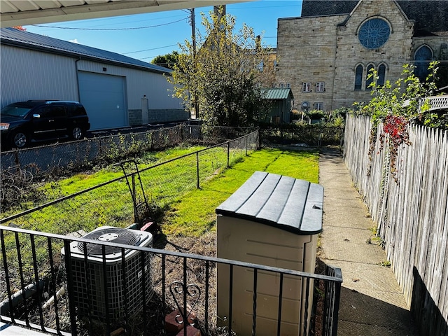 view of yard featuring a garage, cooling unit, and an outdoor structure