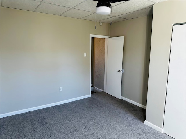 unfurnished bedroom featuring a drop ceiling and carpet floors