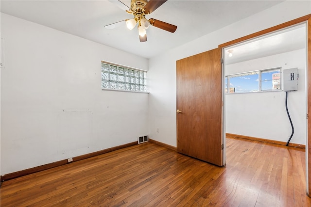 unfurnished bedroom with electric panel, hardwood / wood-style floors, multiple windows, and ceiling fan