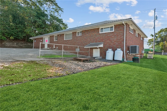 back of property featuring cooling unit and a lawn