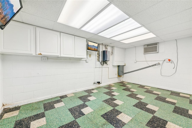 basement featuring a drop ceiling and a wall mounted AC