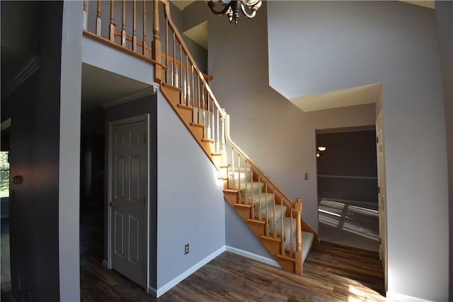 stairway featuring wood-type flooring, an inviting chandelier, and crown molding